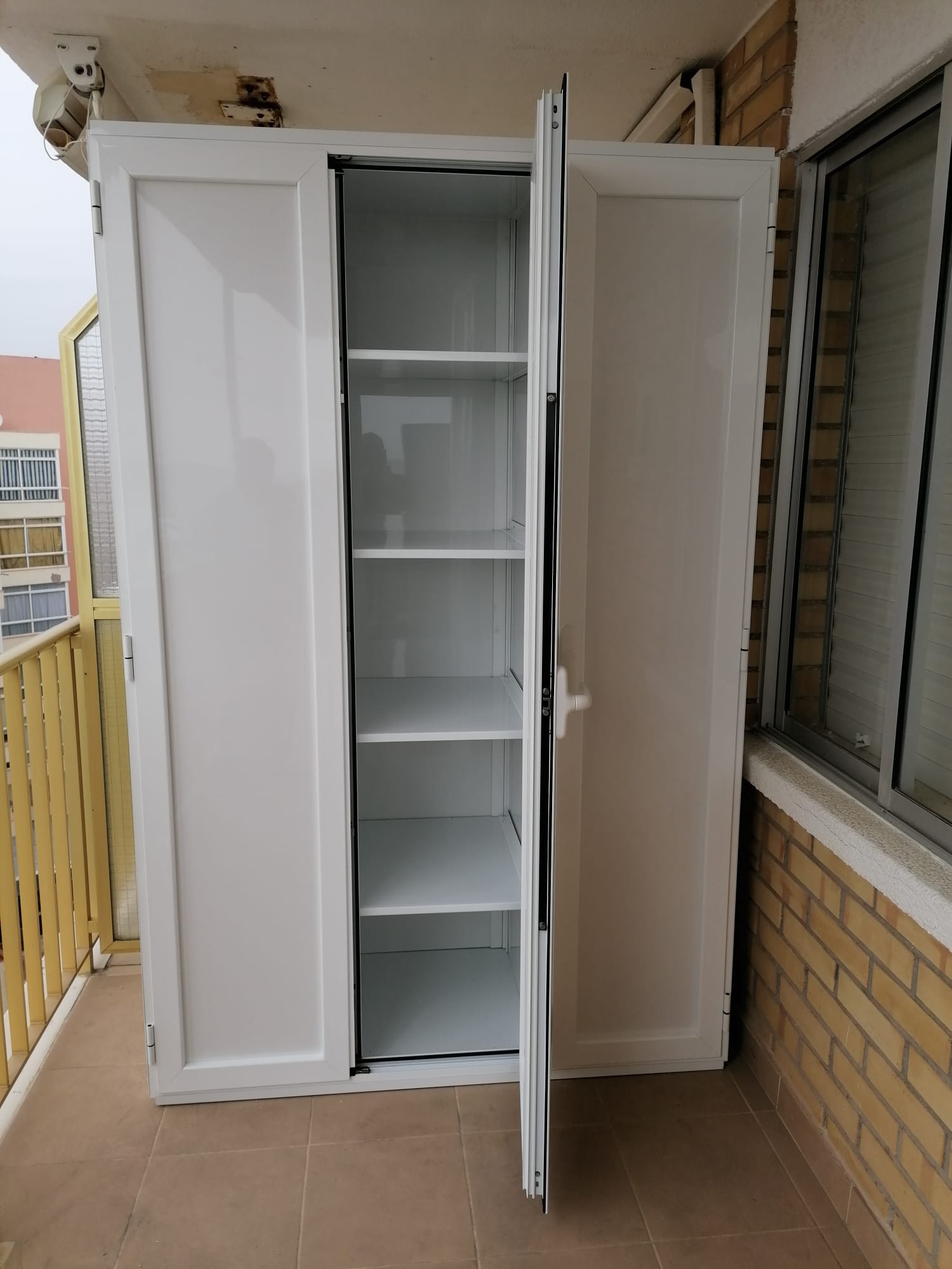Armario de aluminio blanco para exterior y balcón, abierto mostrando las baldas interiores