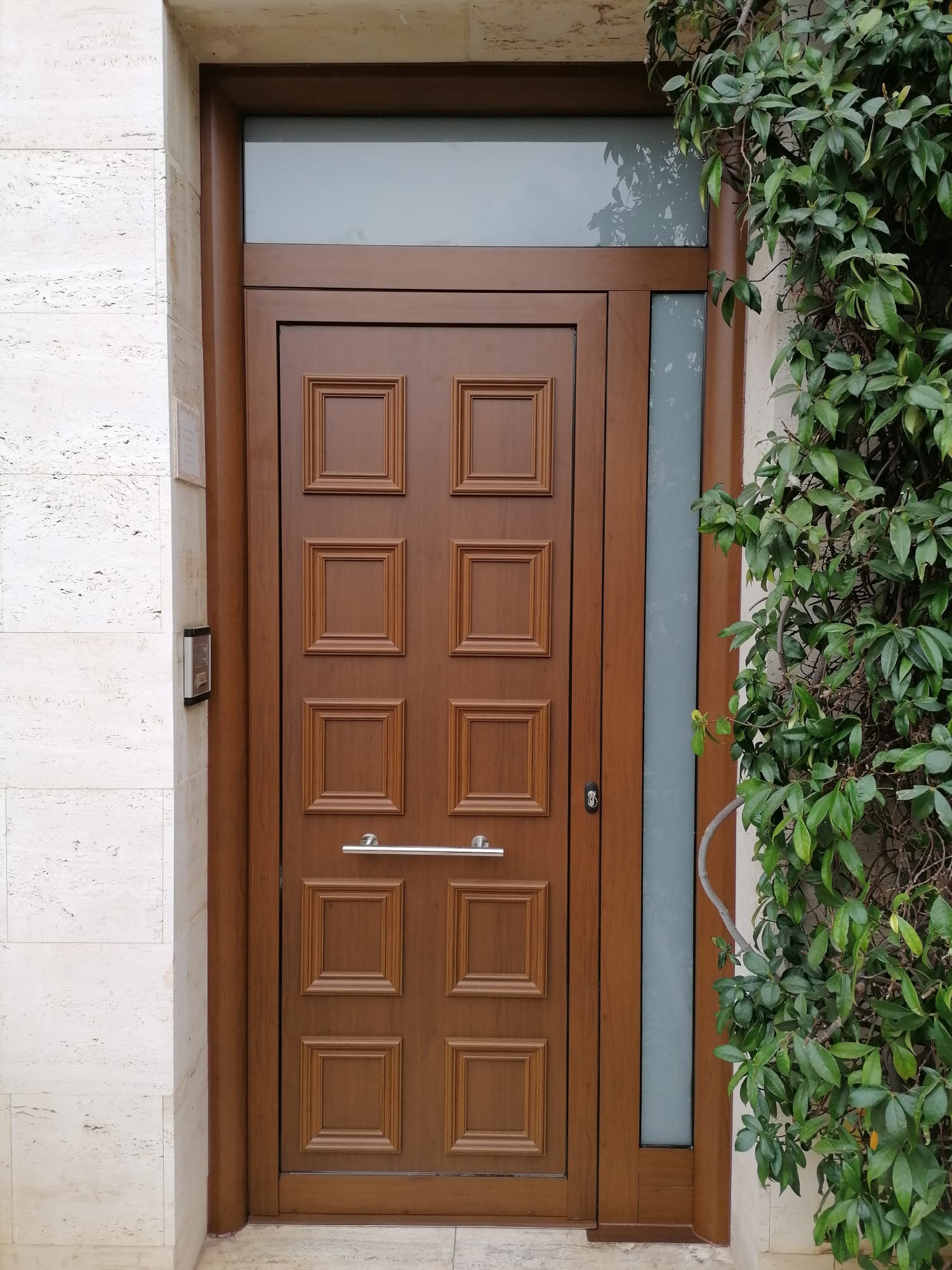 Puerta de entrada clásica imitación madera con paneles cuadrados y fijo lateral acristalado