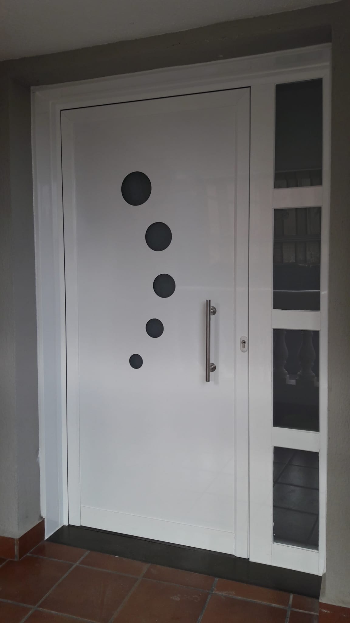 Puerta de entrada minimalista blanca con diseño de ojos de buey y fijo lateral acristalado